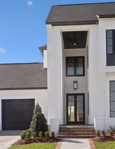 Modern two-story house with a white exterior and black trim, featuring a two-car garage and a tall front entrance.