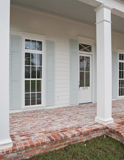 Newly constructed house front with a brick porch and white columns.