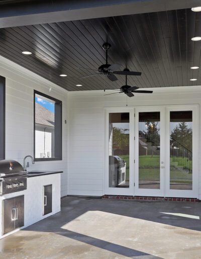 A modern outdoor patio area with a built-in grill and ceiling fans.