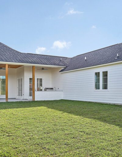 Modern suburban house with a large lawn and gabled roof.