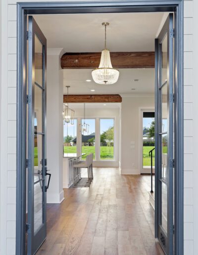 Open doorway leading to an elegant interior with hardwood floors and a chandelier.