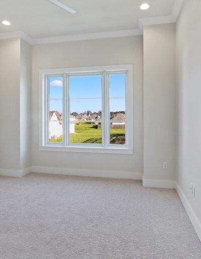 Empty room with carpet flooring and a large window with a view of a grassy area.