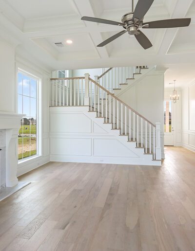 A bright, empty living room with a fireplace and staircase leading to the second floor.