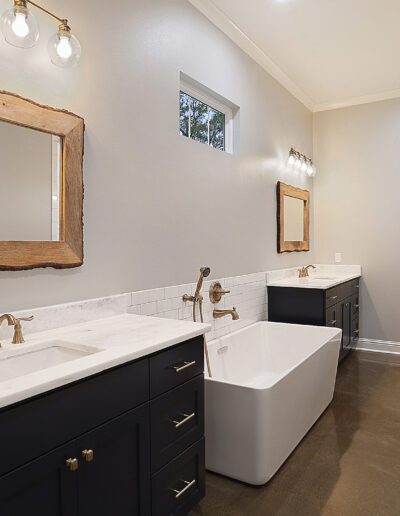 Modern bathroom with dual sinks, a freestanding tub, and a view into an adjoining room.