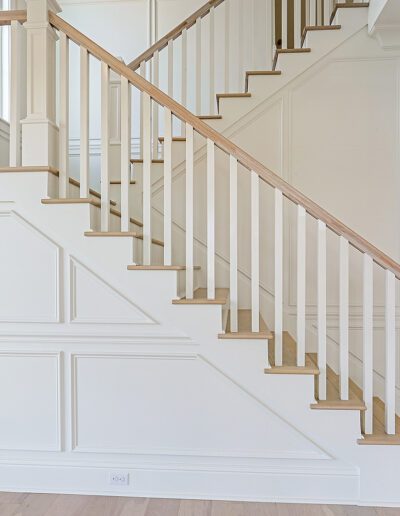 A bright and airy stairway with white balusters and wooden steps in a modern home.