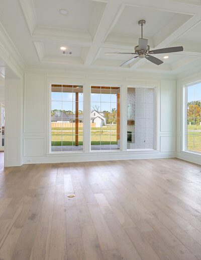 Spacious, empty living room with hardwood floors, large windows, and a fireplace.