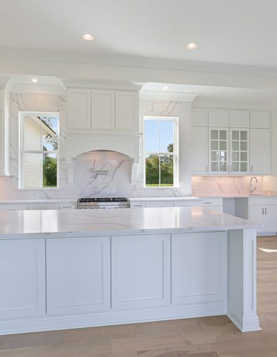 A spacious, modern kitchen with white cabinetry and a central island with a cooktop.