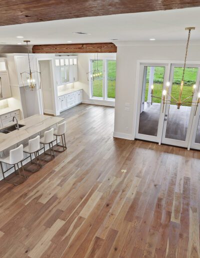 Modern kitchen interior with spacious layout, hardwood floors, white cabinetry, and pendant lighting.