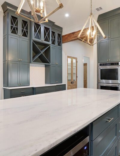 Modern kitchen with blue cabinetry, stainless steel appliances, and a white marble island.