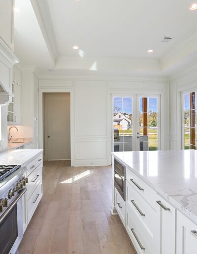 Bright, modern kitchen with white cabinetry, marble countertops, and stainless steel appliances.