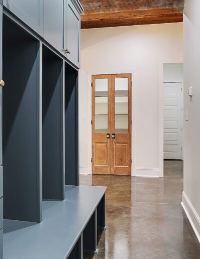 Modern hallway with blue cabinetry, polished concrete floor, and a wooden glass-pane door.