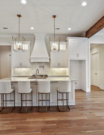 A modern kitchen with white cabinetry, a center island with bar stools, and pendant lighting.