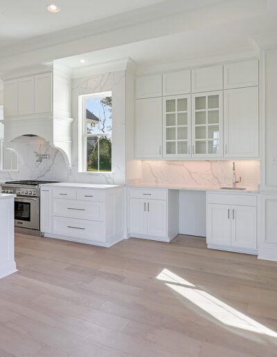 A bright, modern kitchen with white cabinetry and marble countertops.