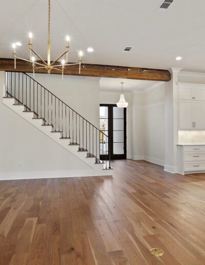 Modern open-plan living space with kitchen, dining area, staircase, and hardwood floors.