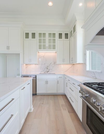 Bright modern kitchen with white cabinetry, stainless steel appliances, and marble countertops.