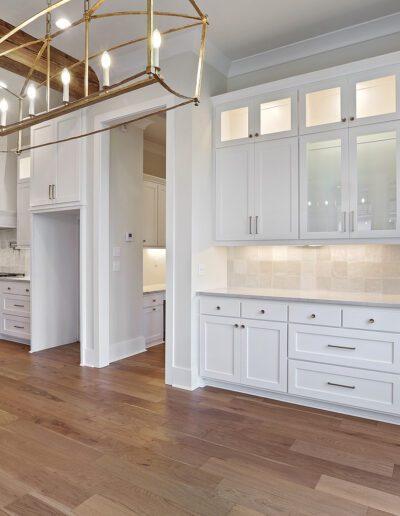 Modern kitchen interior with white cabinetry, stainless steel appliances, and hardwood floors.