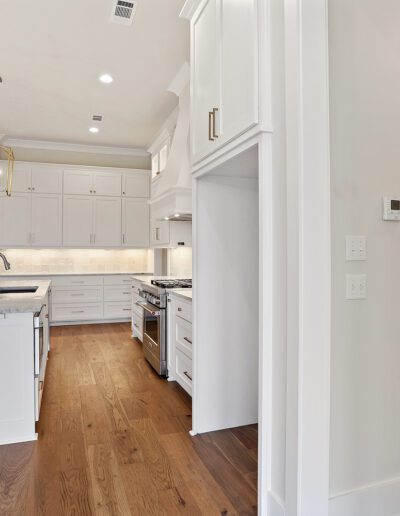 Modern kitchen interior with white cabinetry, stainless steel appliances, and hardwood floors.