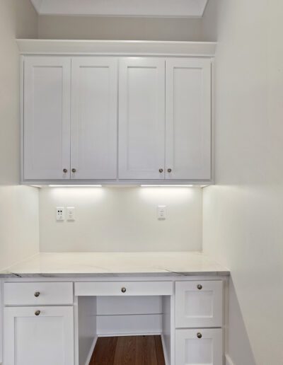 A clean, uncluttered home office nook with white cabinetry and under-cabinet lighting.