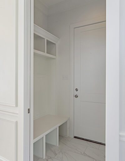 A bright, empty corner in a room featuring a built-in bench with storage and open shelving next to a closed white door.