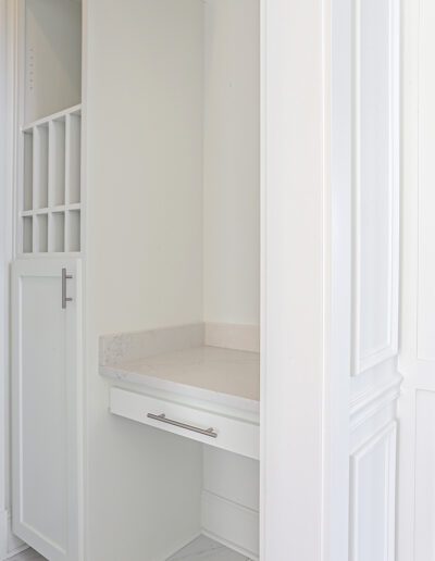 A white built-in wardrobe with an integrated small desk and drawers in a minimalist design.