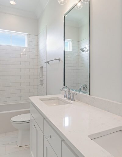 A bright, modern bathroom with dual sinks, a large mirror, a bathtub, and a separate shower area.