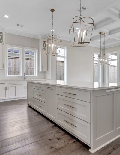 A bright, modern kitchen with white cabinetry, stainless steel appliances, and a central island under elegant pendant lights.