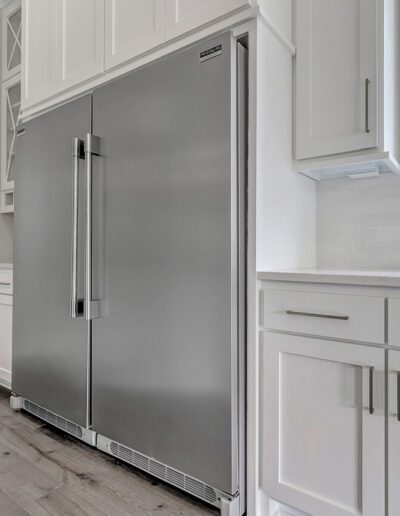 Modern kitchen interior with stainless steel refrigerator and white cabinetry.