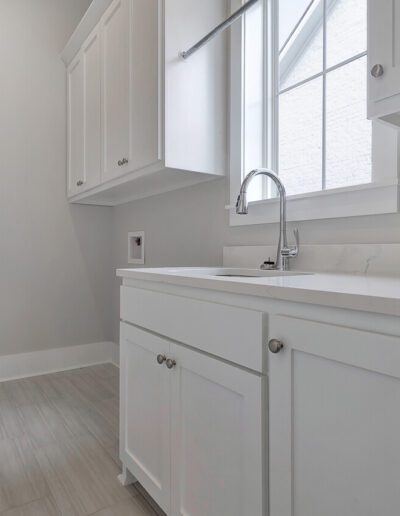 Modern kitchen corner with white cabinetry and countertops featuring a window above the sink.