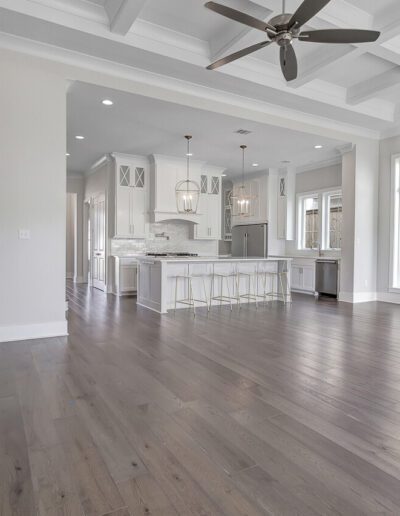 An open-plan living space with a kitchen, hardwood floors, a fireplace, and modern lighting fixtures.