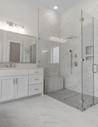 A modern bathroom with a glass-enclosed shower, double vanity, and built-in shelving.