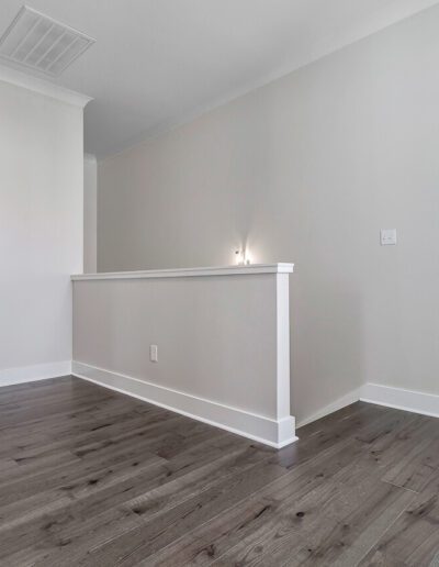 An empty room with white walls, chair railing, and dark wood flooring.